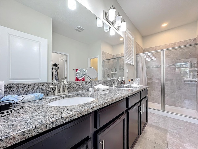 bathroom featuring double vanity, a shower stall, visible vents, and a sink