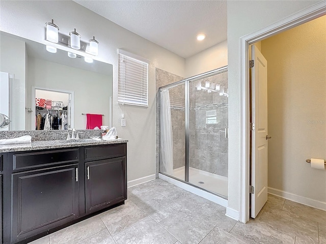 full bath with a stall shower, a walk in closet, a textured ceiling, and baseboards