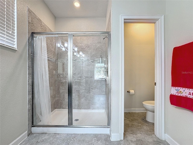 full bathroom featuring toilet, a shower stall, and baseboards