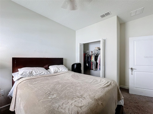 bedroom featuring a closet, visible vents, dark carpet, and a textured ceiling