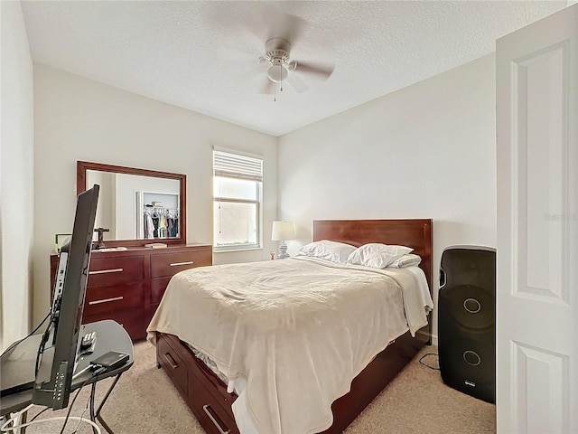 bedroom featuring light carpet, a ceiling fan, and a textured ceiling