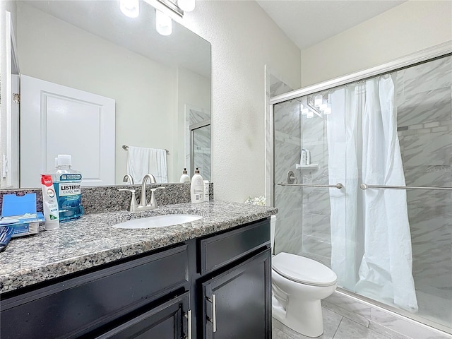 bathroom with toilet, a shower stall, and vanity