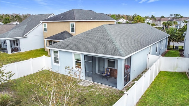 back of house with a sunroom, a yard, a fenced backyard, and a residential view