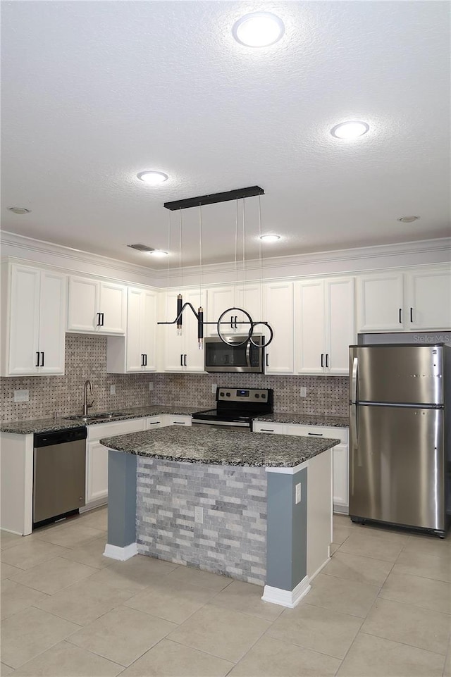 kitchen with a kitchen island, dark stone countertops, white cabinets, and stainless steel appliances