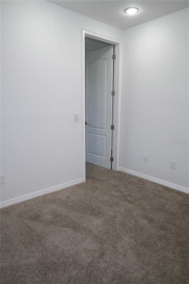 empty room featuring carpet, baseboards, and a textured ceiling