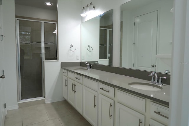 bathroom with a sink, double vanity, a shower stall, and tile patterned floors