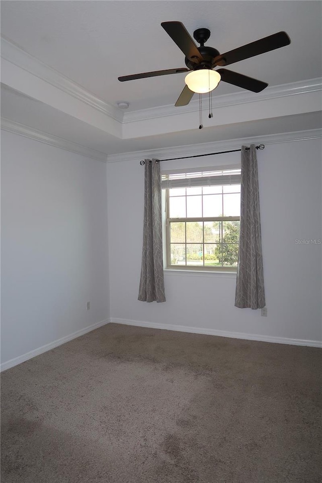carpeted empty room featuring baseboards, a raised ceiling, ceiling fan, and crown molding