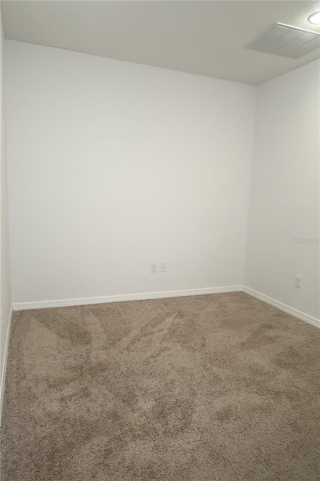 spare room with visible vents, carpet floors, and baseboards