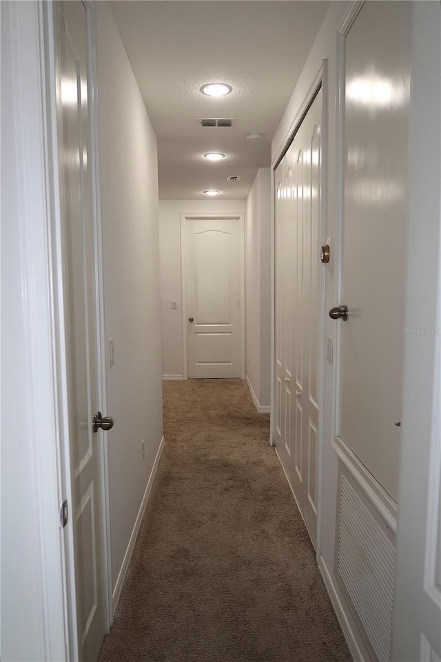 corridor featuring visible vents, baseboards, and carpet flooring