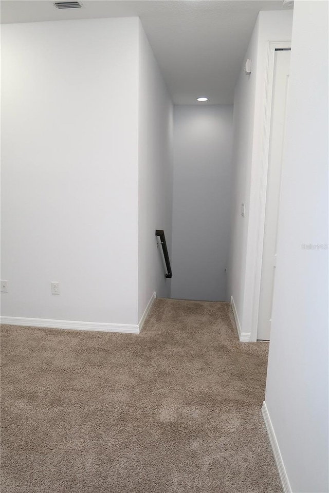corridor with visible vents, an upstairs landing, baseboards, and carpet floors