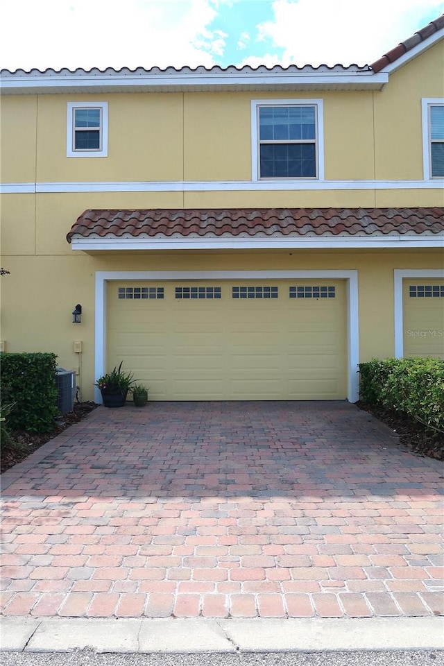 garage featuring decorative driveway and cooling unit