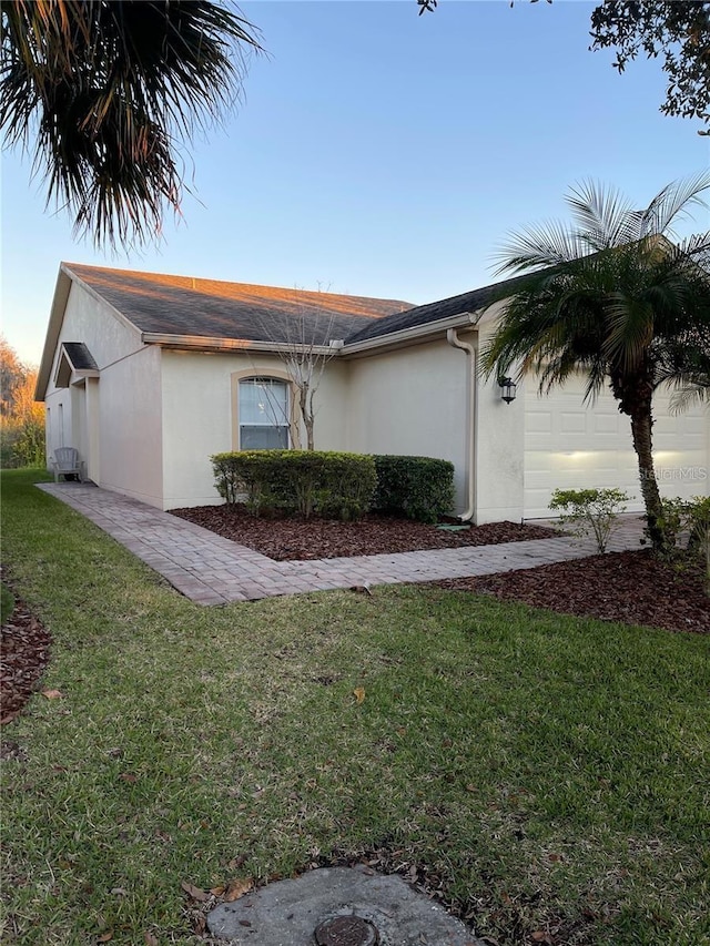 view of home's exterior with a yard, an attached garage, and stucco siding