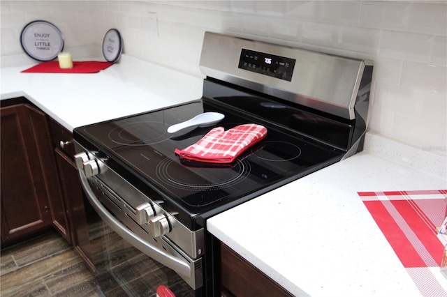 kitchen featuring dark brown cabinetry, electric range, light countertops, and dark wood finished floors