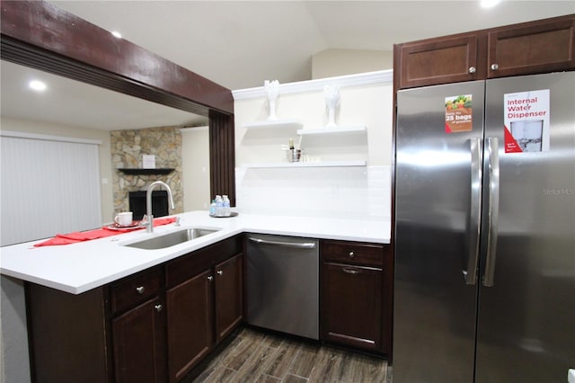 kitchen with dark wood-style floors, light countertops, appliances with stainless steel finishes, a sink, and a peninsula