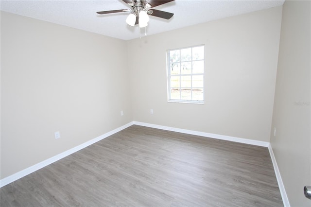 unfurnished room with a ceiling fan, a textured ceiling, baseboards, and wood finished floors