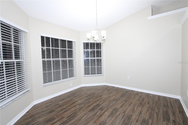 empty room featuring an inviting chandelier, baseboards, and wood finished floors