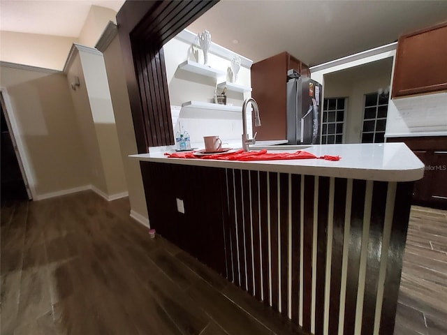 kitchen with a sink, wood finished floors, baseboards, light countertops, and freestanding refrigerator