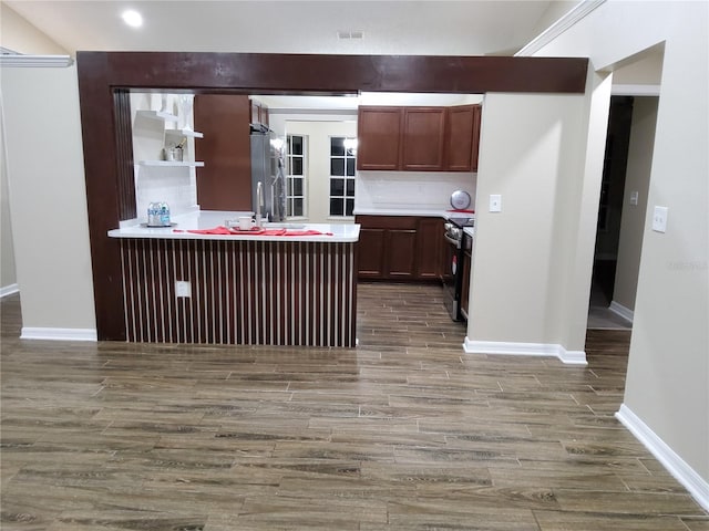 kitchen featuring wood finished floors, a peninsula, stainless steel appliances, light countertops, and open shelves