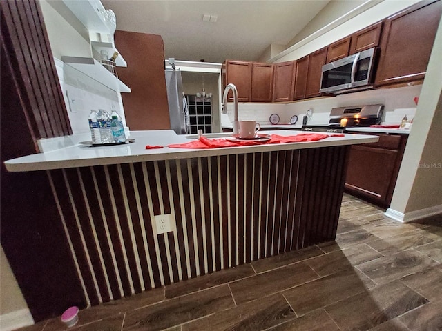 kitchen featuring lofted ceiling, light countertops, appliances with stainless steel finishes, and wood tiled floor