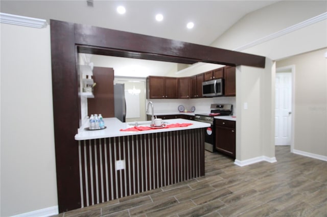 kitchen with dark brown cabinetry, stainless steel appliances, a peninsula, wood finished floors, and light countertops