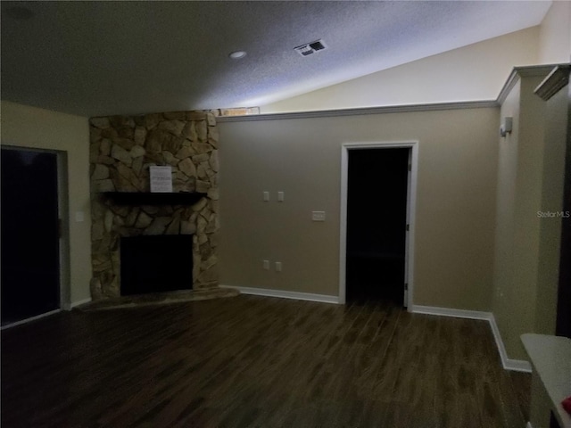 unfurnished living room featuring visible vents, vaulted ceiling, a stone fireplace, and wood finished floors