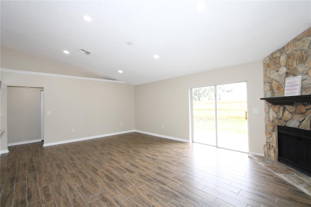 unfurnished living room with lofted ceiling, visible vents, a stone fireplace, and wood finished floors