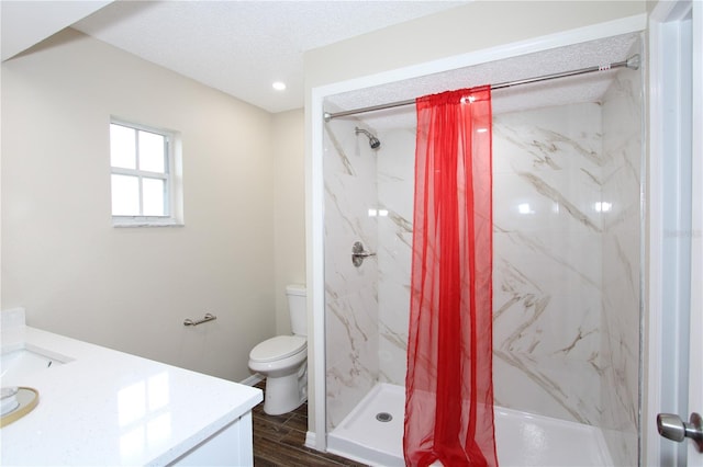 bathroom with a marble finish shower, toilet, a textured ceiling, vanity, and wood finished floors