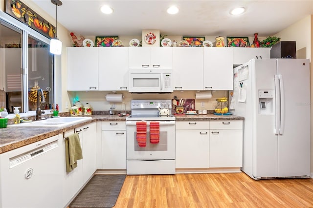 kitchen with white appliances, white cabinetry, a sink, and decorative light fixtures