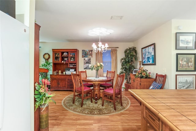 dining space featuring visible vents, a notable chandelier, and light wood-style flooring