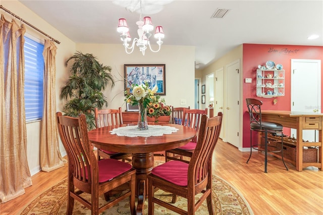 dining space with light wood-type flooring, an inviting chandelier, baseboards, and visible vents