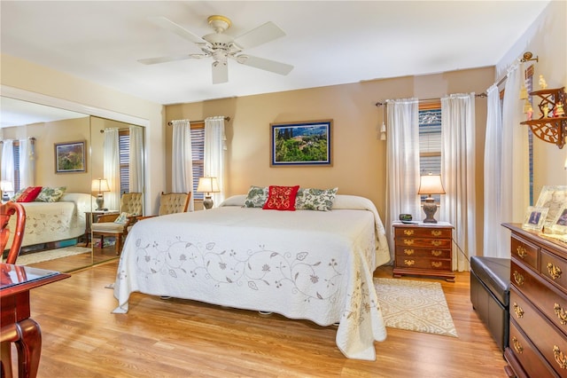 bedroom featuring a ceiling fan, a closet, multiple windows, and light wood-style flooring