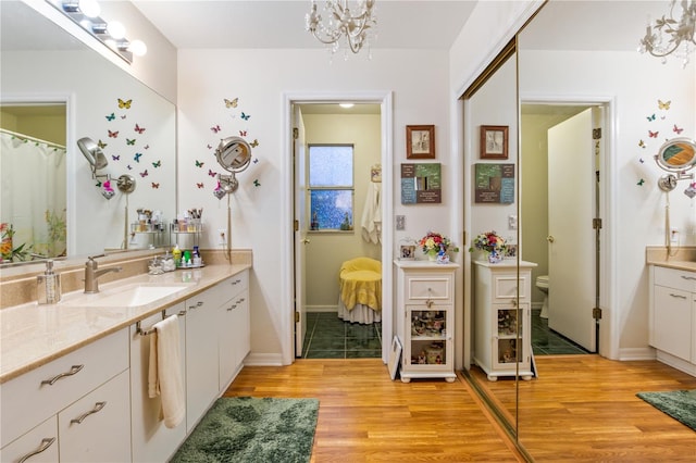 ensuite bathroom with toilet, wood finished floors, ensuite bathroom, vanity, and a chandelier