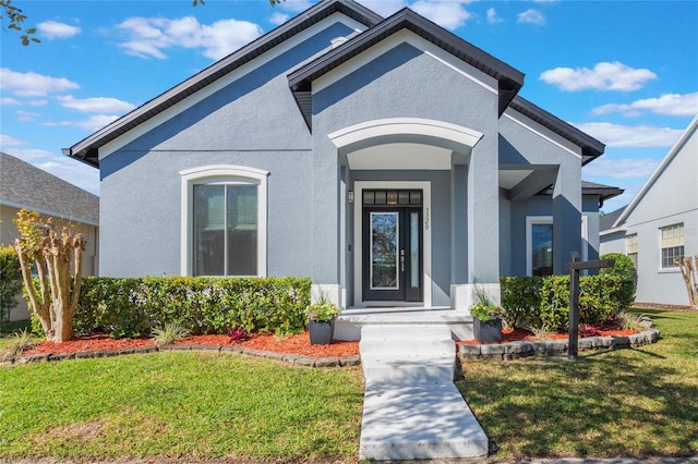 doorway to property featuring a yard and stucco siding