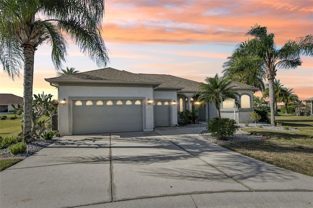 view of front of house featuring a garage, driveway, a front lawn, and stucco siding