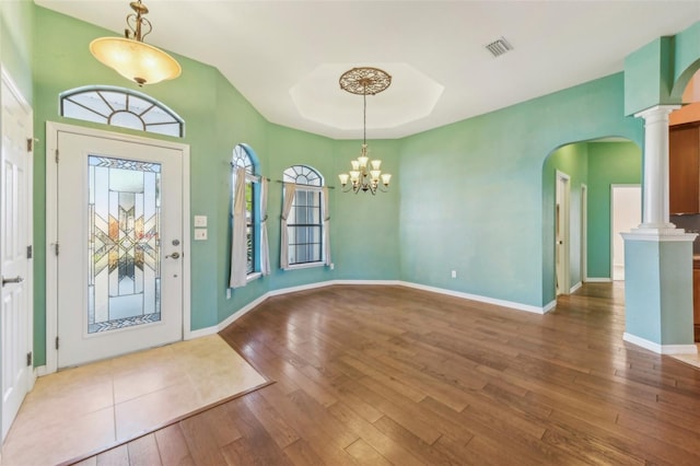 entrance foyer with decorative columns, arched walkways, dark wood finished floors, and baseboards