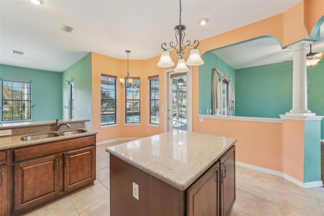 kitchen with a center island, a sink, hanging light fixtures, and decorative columns