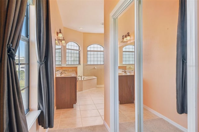 bathroom featuring a garden tub, vanity, and tile patterned floors