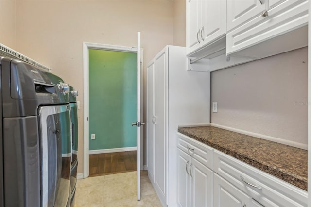 clothes washing area with washer / clothes dryer, cabinet space, baseboards, and light tile patterned floors