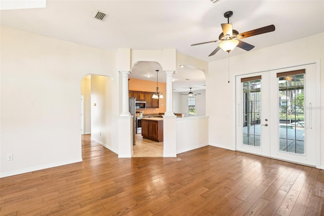 12018 SE 175th Loop, Summerfield, FL 34491 - unfurnished living room featuring arched walkways, decorative columns, a ceiling fan, french doors, and light wood-style floors
