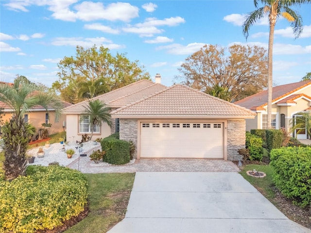 ranch-style house with a garage, stone siding, a chimney, a tiled roof, and decorative driveway