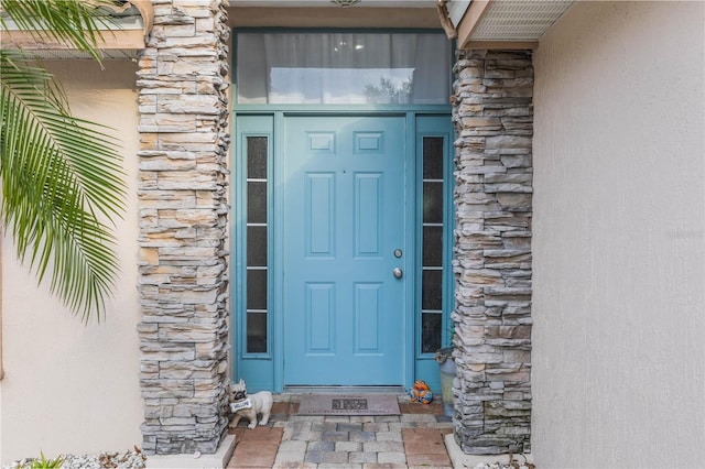 property entrance with stone siding and stucco siding