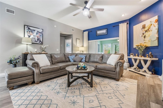 living room with visible vents, ceiling fan, baseboards, and wood finished floors