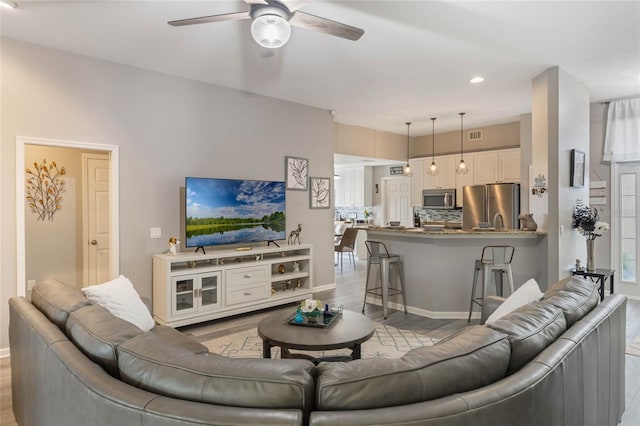 living room with visible vents, baseboards, ceiling fan, light wood-style floors, and recessed lighting