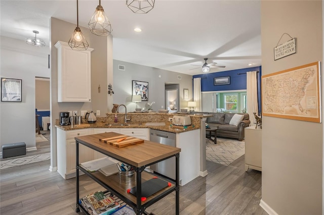 kitchen with light wood-style flooring, a peninsula, a sink, white cabinetry, and dishwasher