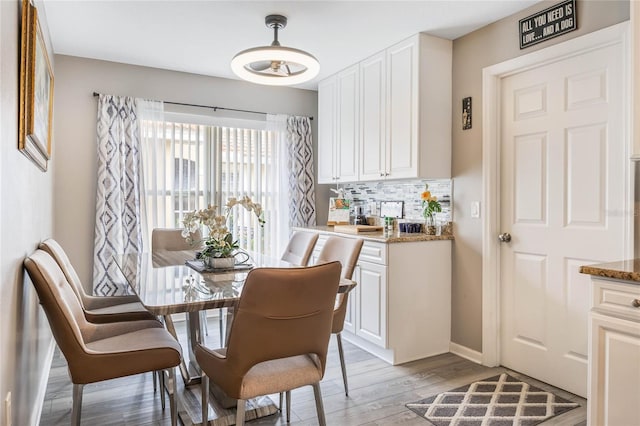 dining space with baseboards and light wood-style floors