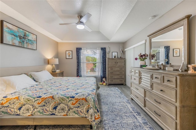 bedroom featuring light wood-type flooring, ceiling fan, a tray ceiling, and a sink