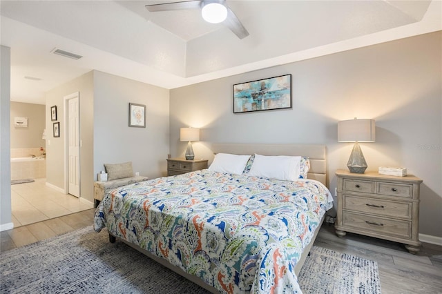 bedroom featuring baseboards, visible vents, ceiling fan, wood finished floors, and ensuite bathroom