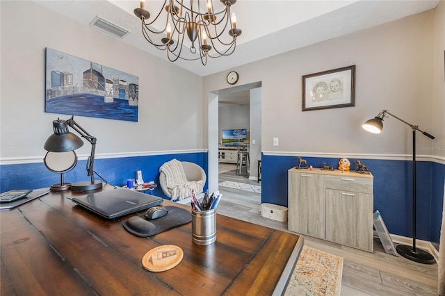 home office featuring visible vents, a notable chandelier, and wood finished floors