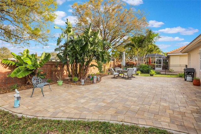 view of patio / terrace featuring a lanai, a fenced backyard, and grilling area