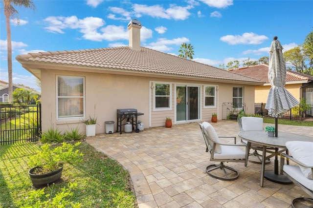 rear view of property with a patio area, fence, a chimney, and stucco siding